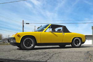 A completely restored yellow Porsche 914 posing in the parking lot of Lufteknic.