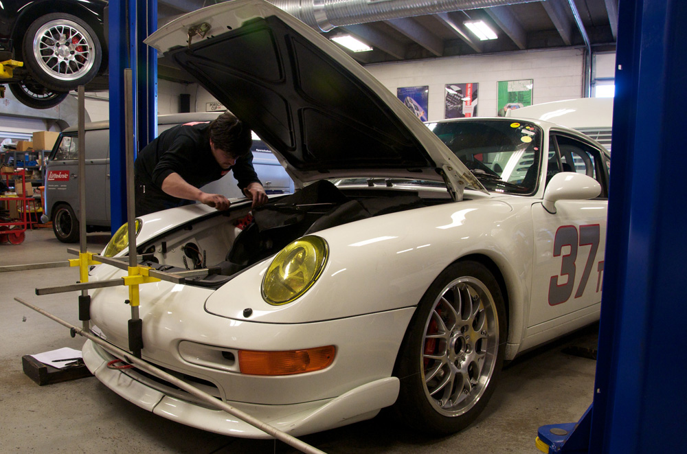 A Lüfteknic technician working on a white 993 911 race car.