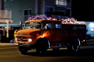 A 1964 Mercedes fire truck with christmas lights driving down coastal highway at h2oi.