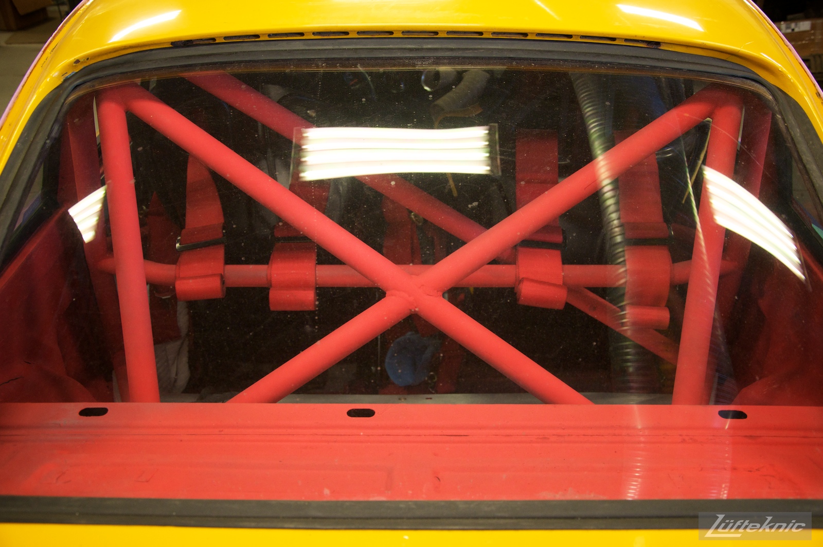 The beefy red roll cage of Lüfteknic #projectstuka Porsche 930 Turbo framed by yellow paint
