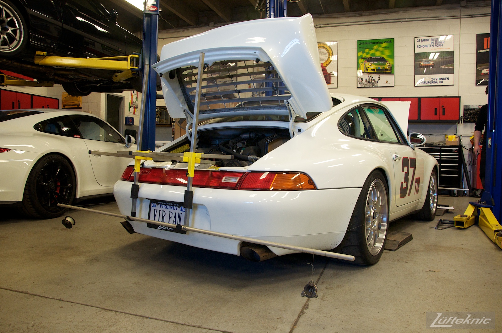 A white Porsche 993 race car inside the Lufteknic shop with alignment strings attached.