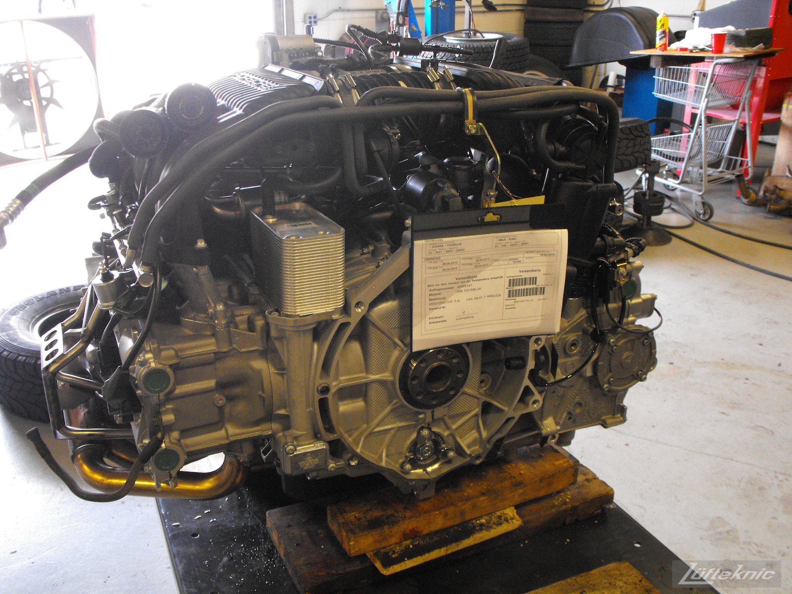 A brand new M96 Porsche motor sits on an engine table with technical sheet attached.