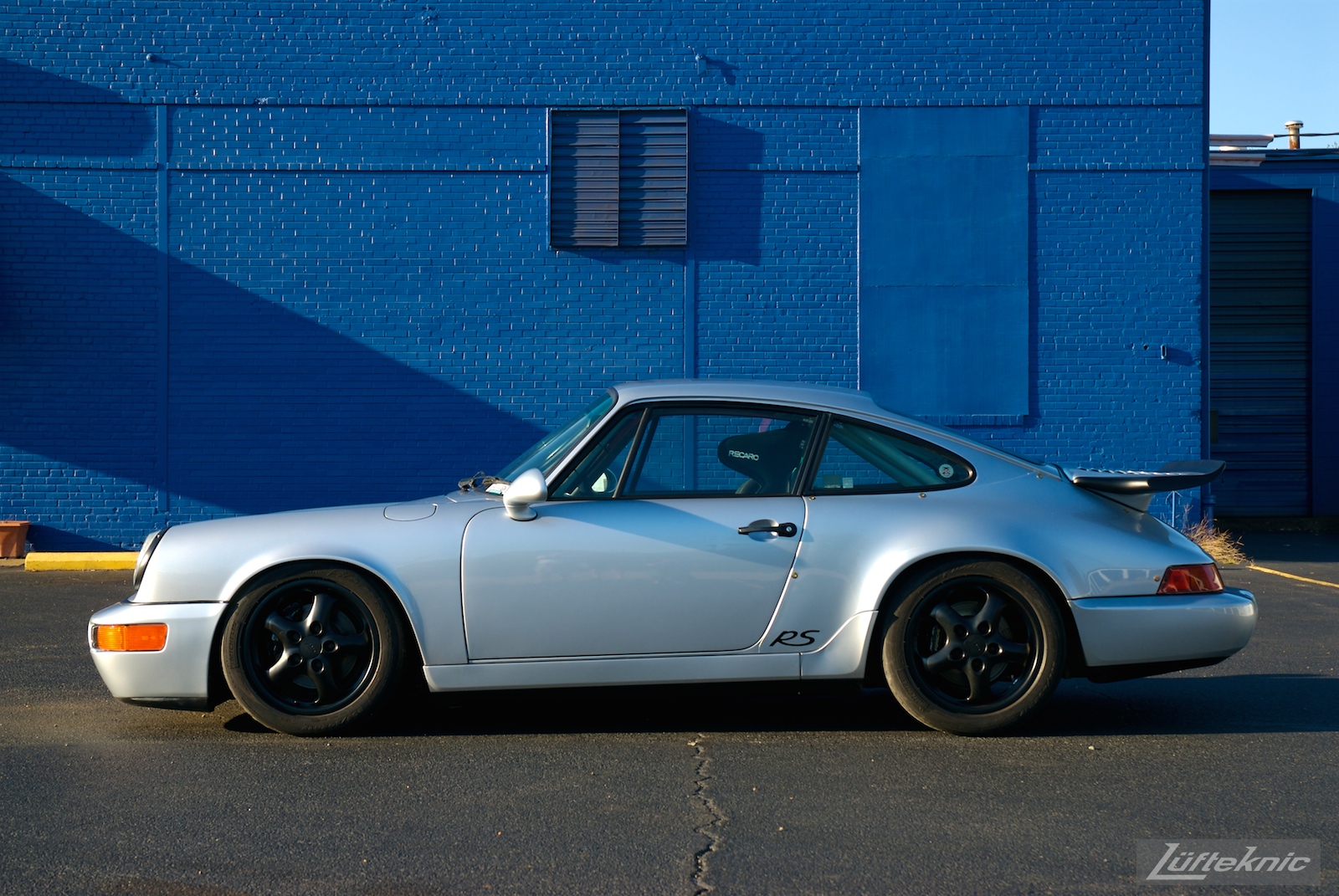 Track prepped Porsche 964 RS America in front of a blue wall.