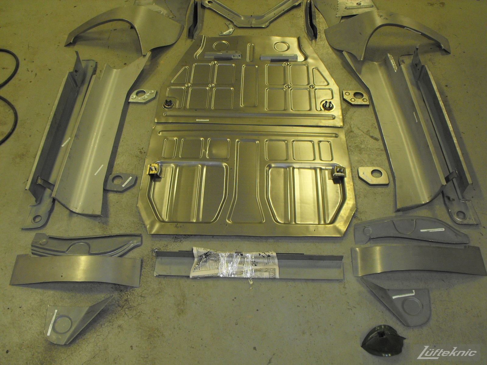 New floors and panels laid out on the ground for a 1961 Porsche 356B Roadster restoration.
