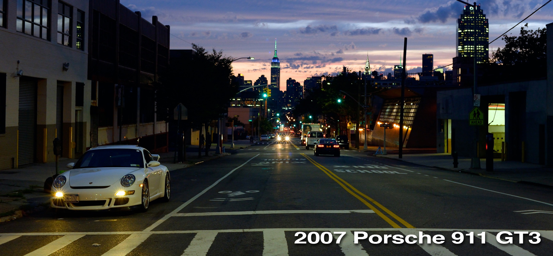 A white 997 GT3 on 42nd street in queens with the empire state building visible.