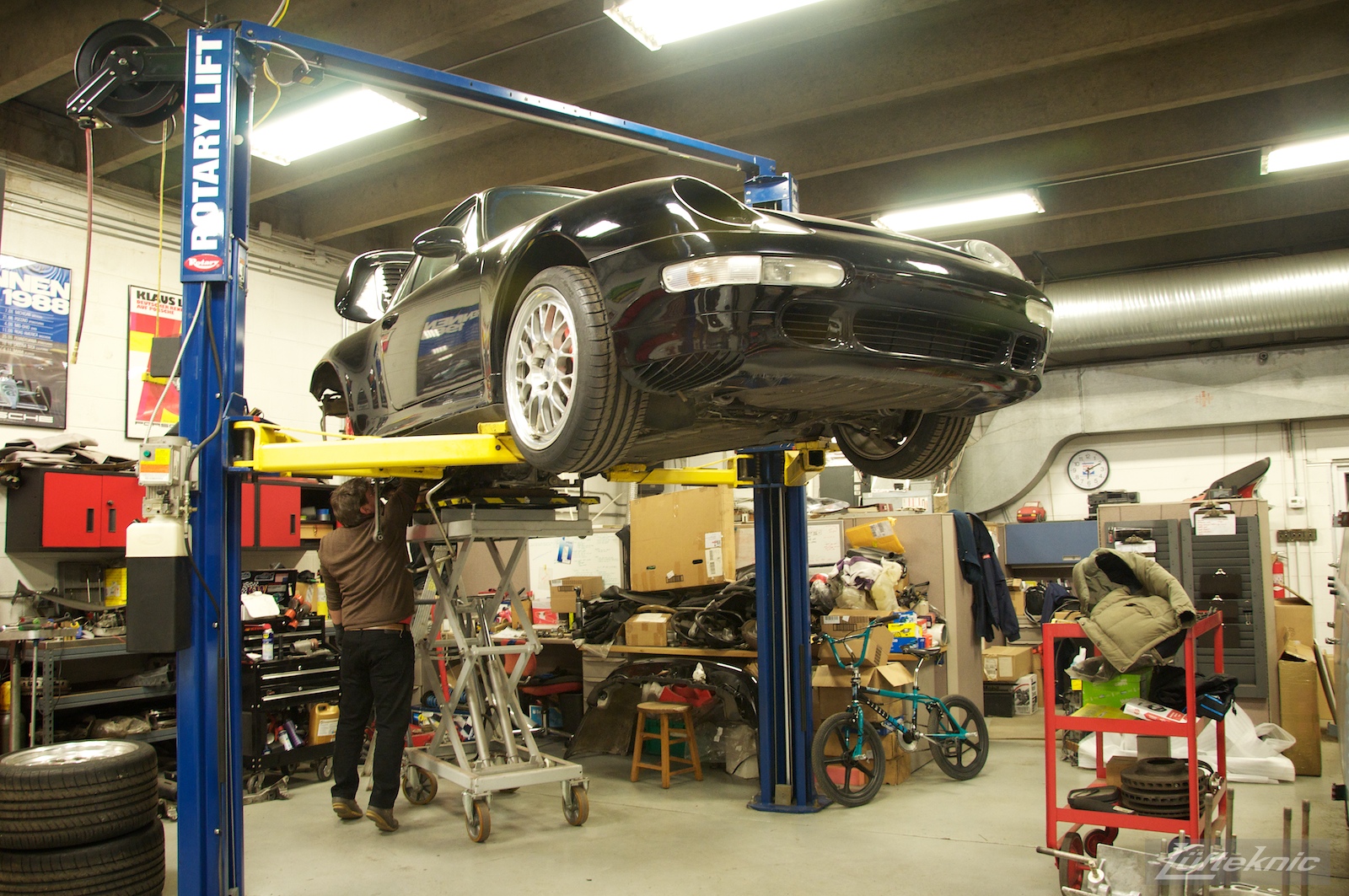 A shot from the front showing a 993 Turbo on a lift with the engine stand lifting the driveline into the car