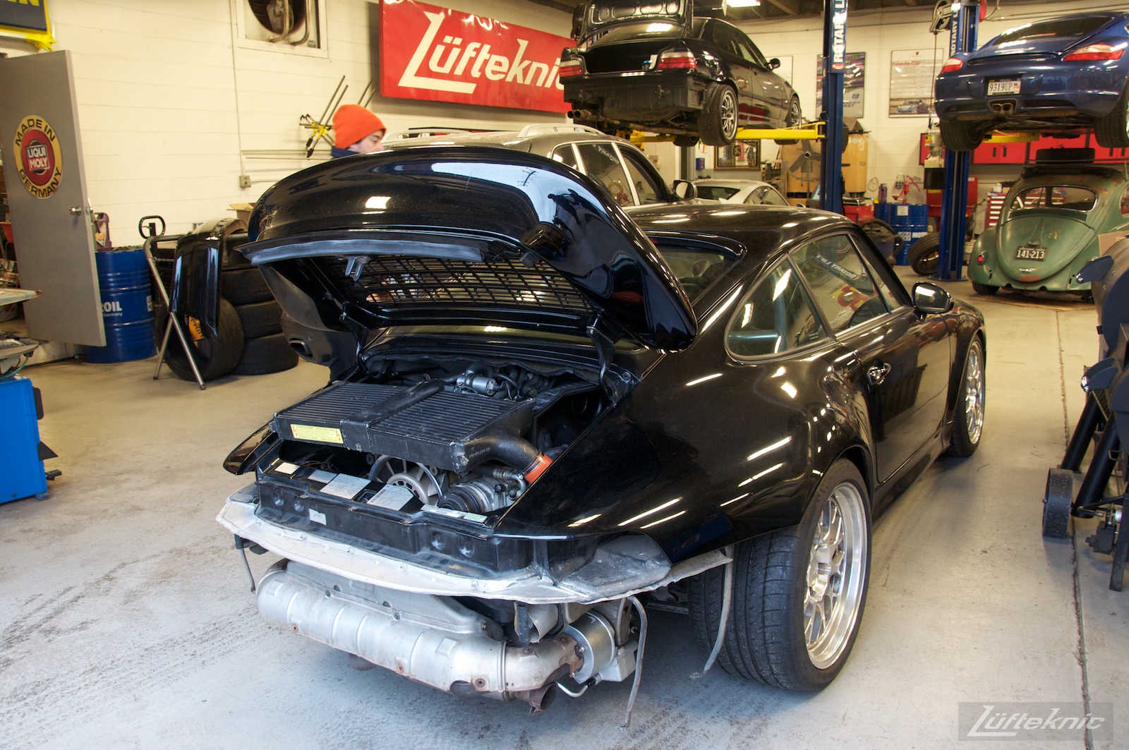 993 Turbo with no rear bumper sitting staged inside the Lufteknic shop with other cars inside the shop.
