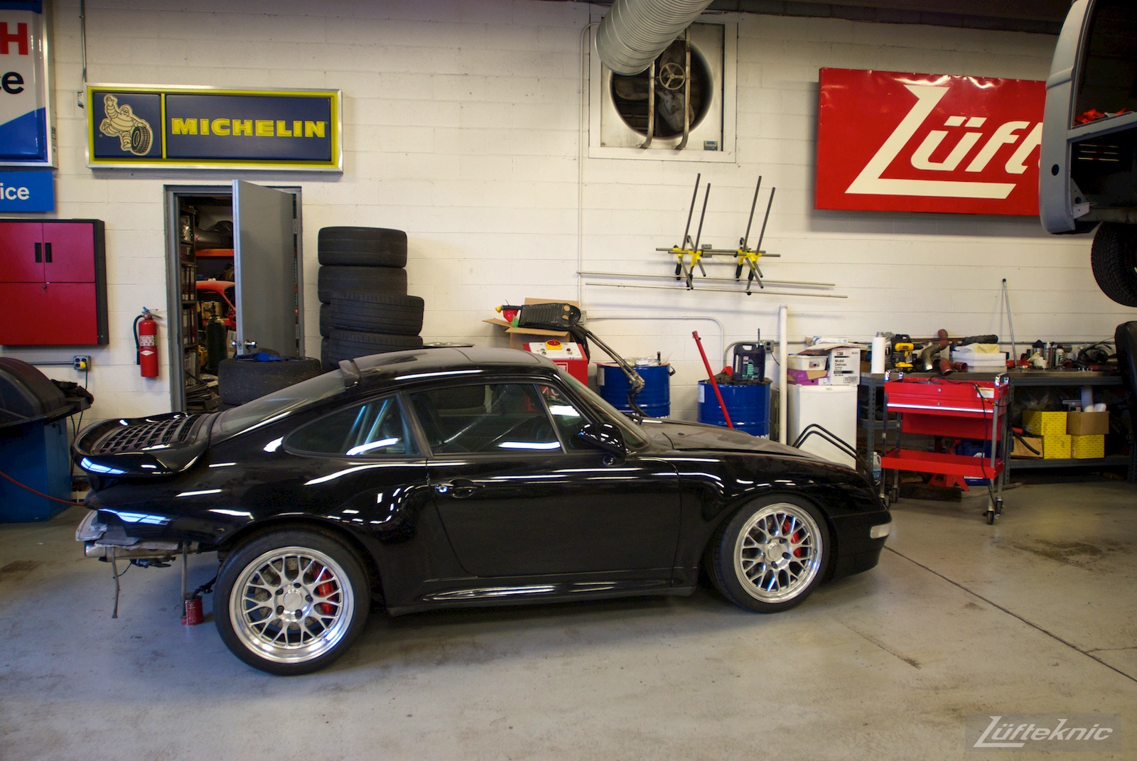 A black 993 Turbo sitting in the Lufteknic shop with the engine removed.