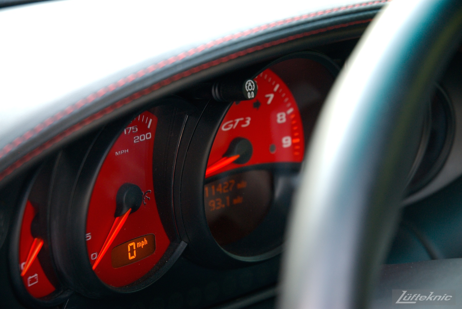 A track-prepped white Porsche 996 Gt3 with red gauges