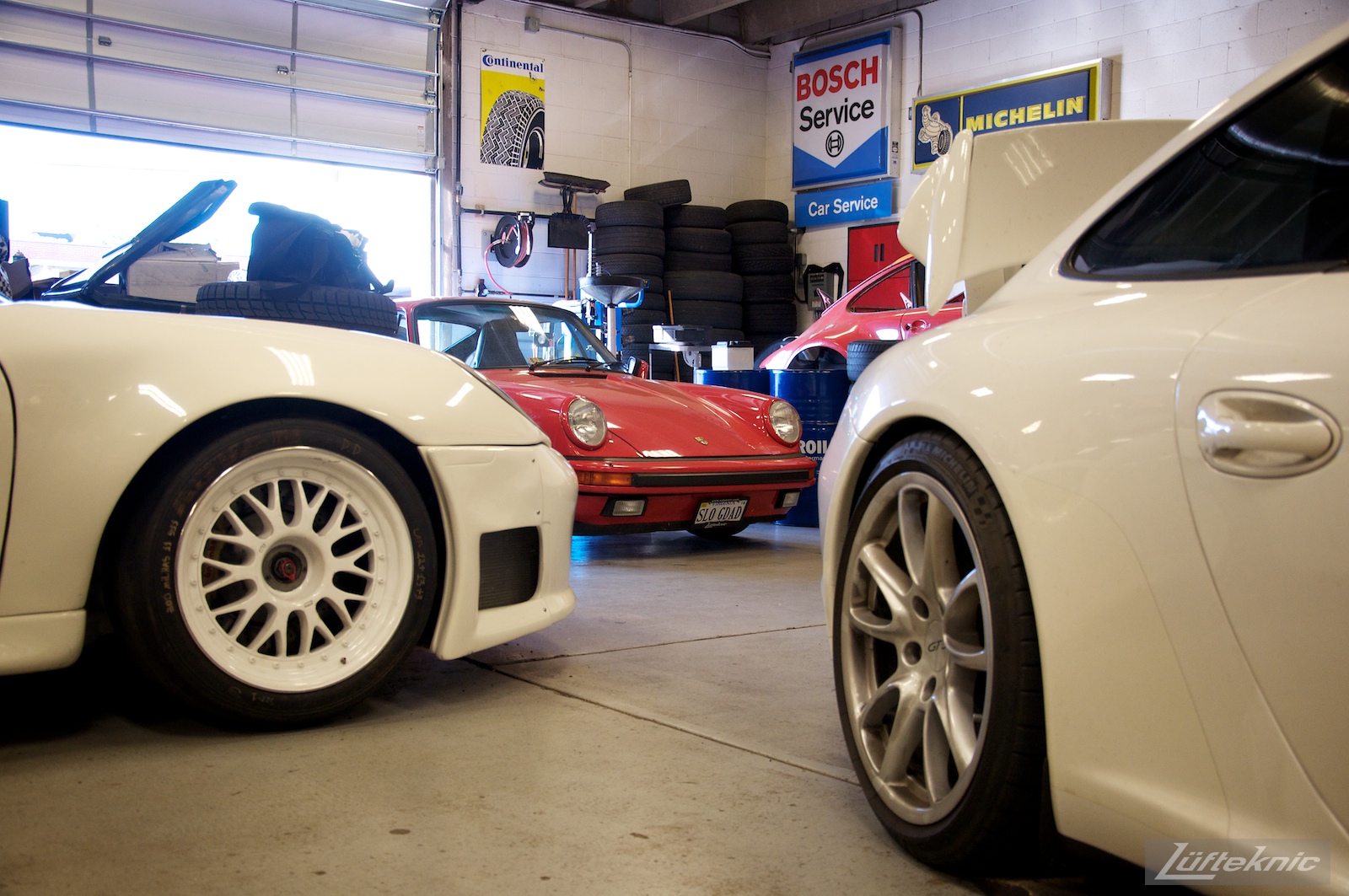 Two white Porsches and one red Porsche inside the Lufteknic shop.