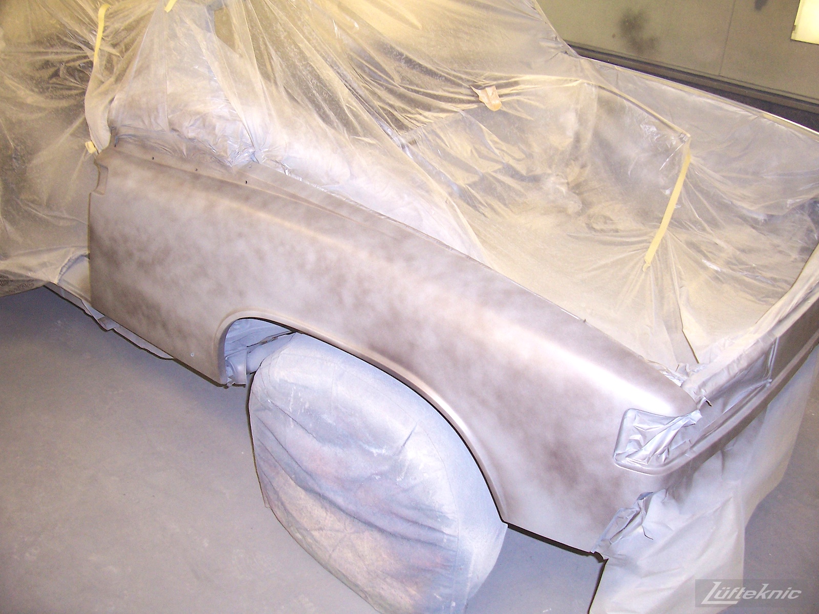A porsche 914 with primer applied to the fender while everything else is taped off.