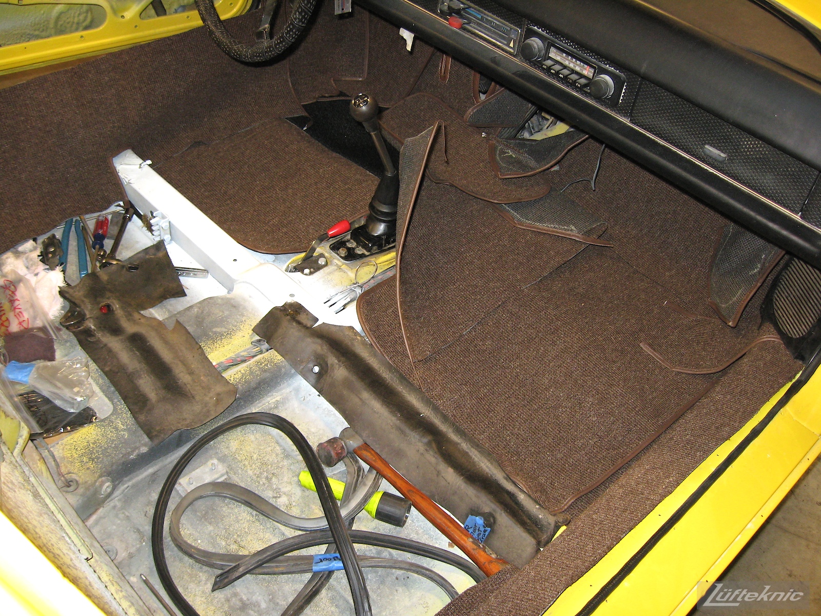 Interior carpets being installed into a yellow Porsche 914 being restored by Lufteknic.