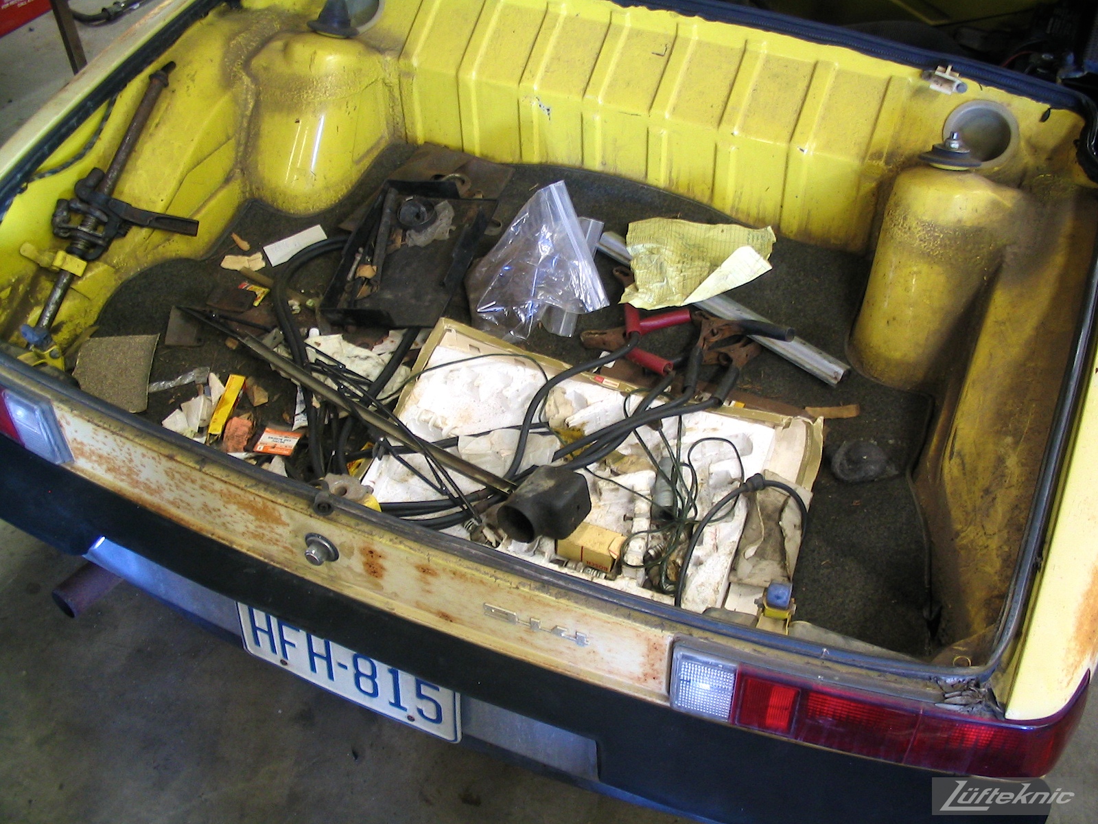 Various debris in the trunk of a yellow 914 before restoration.