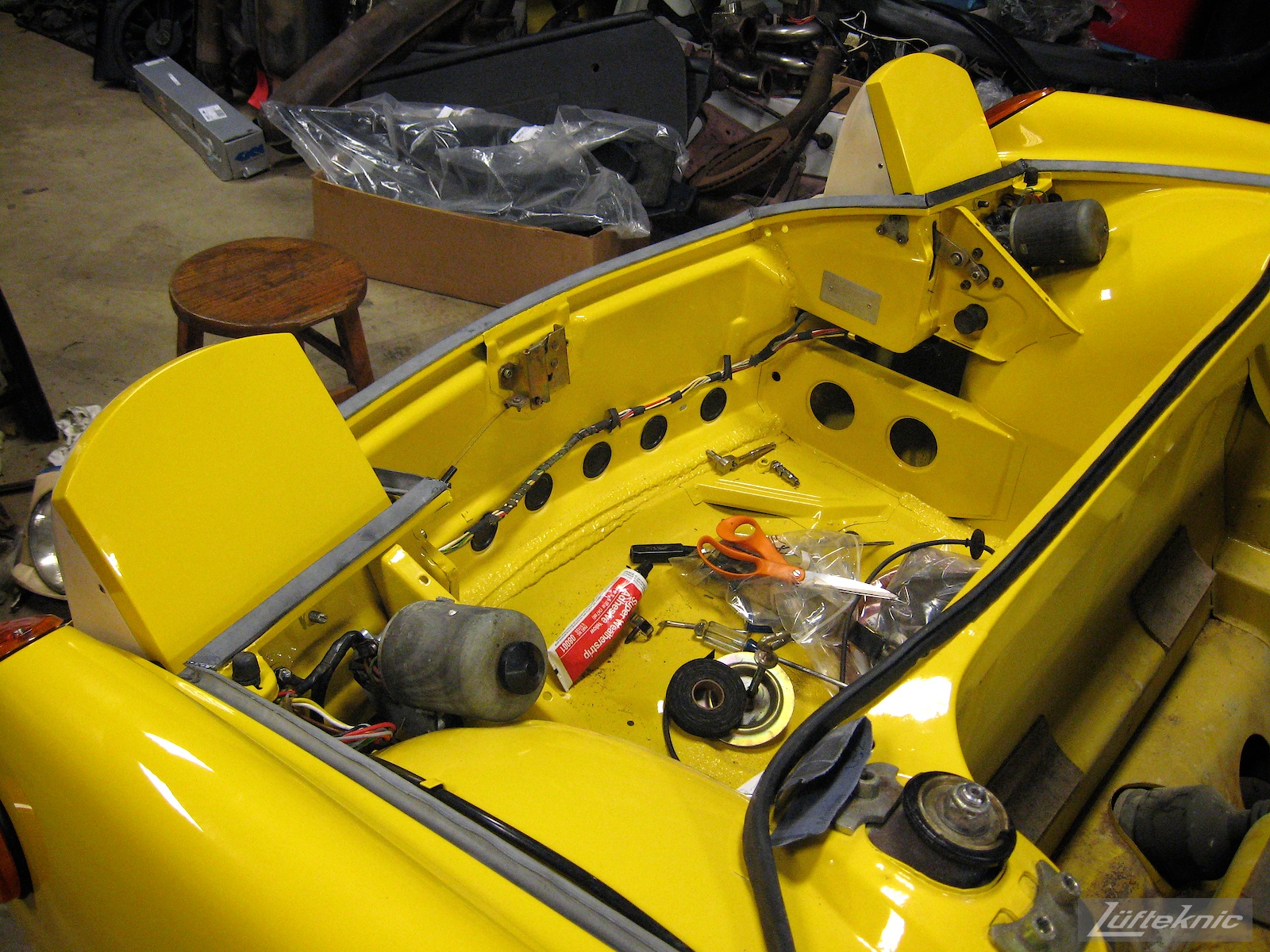 Reassembling headlights and lighting on a restored yellow Porsche 914 at Lufteknic.