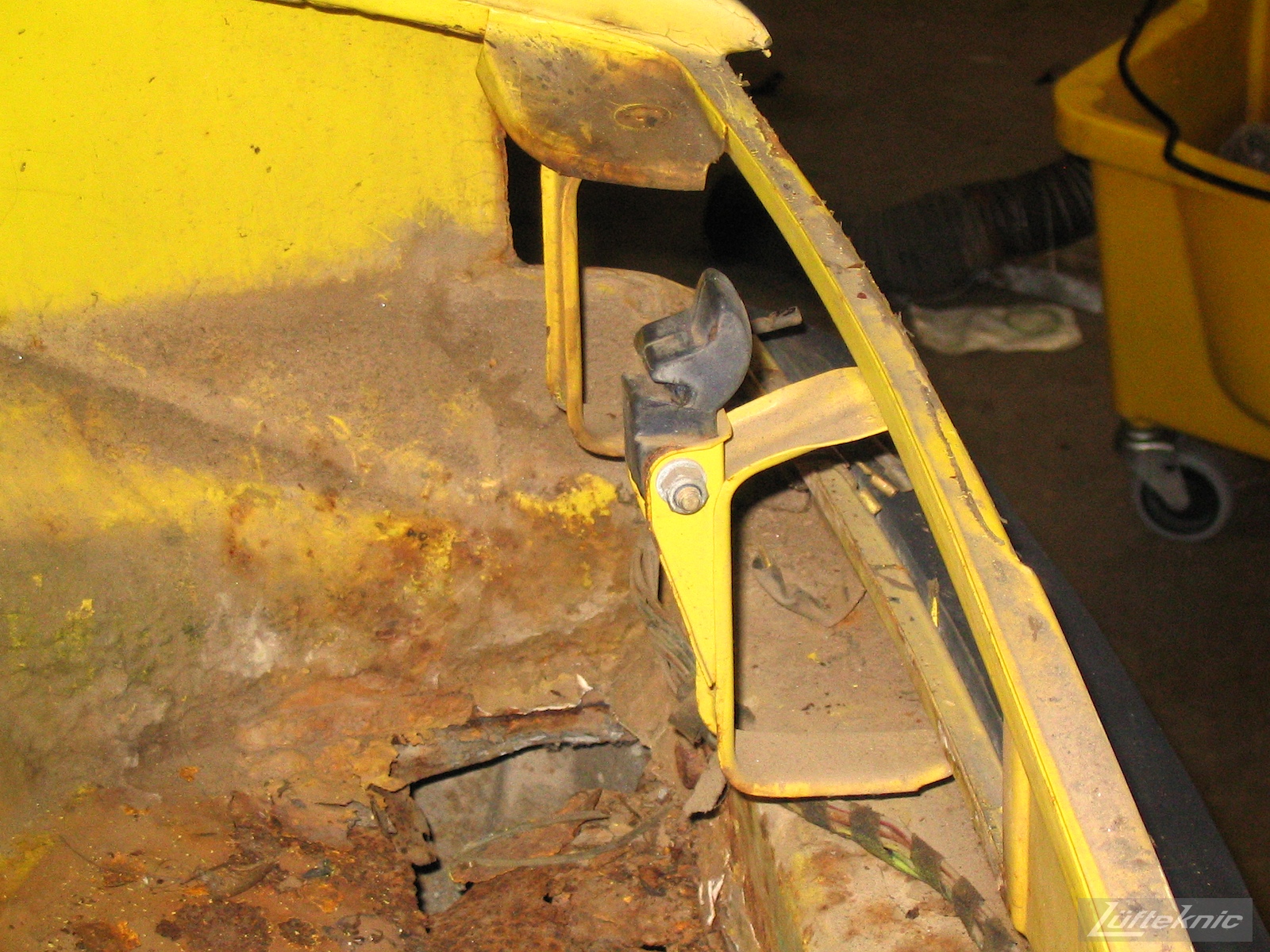 Significant rust damage on the chassis of a yellow Porsche 914.