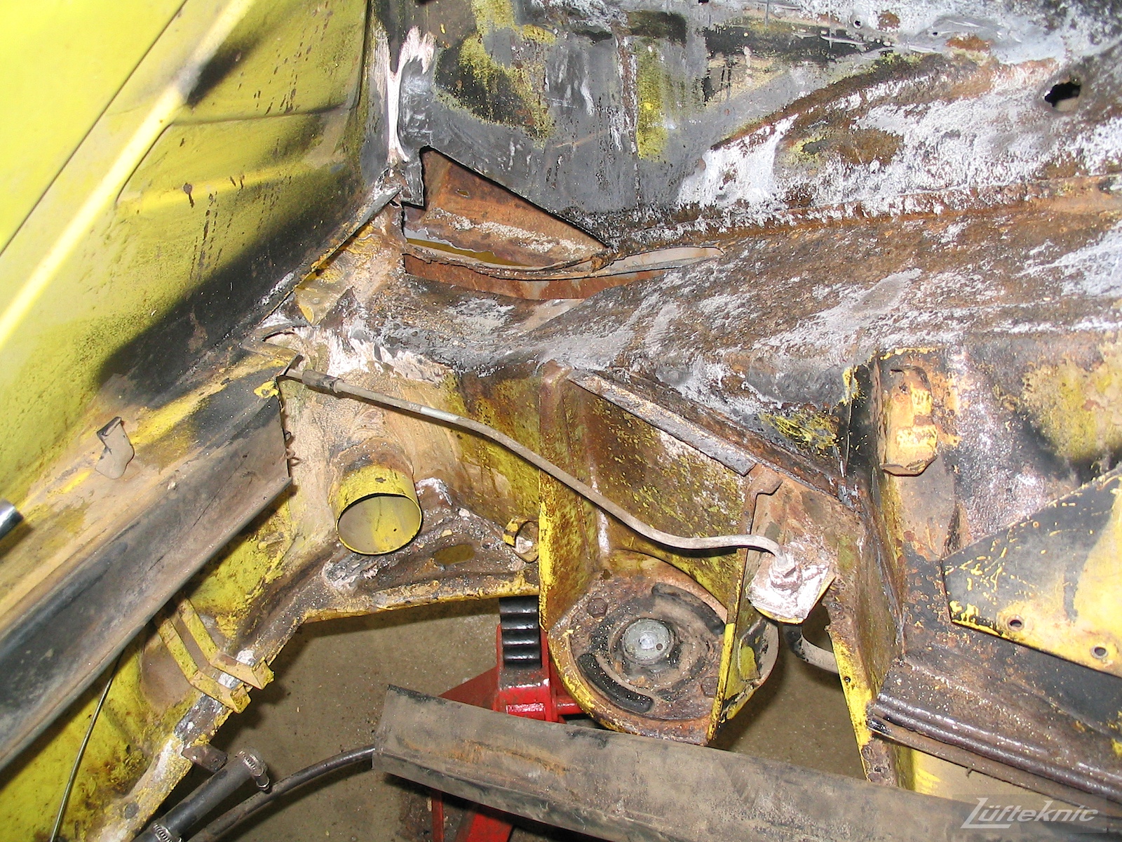 Significant rust damage on the chassis of a yellow Porsche 914.