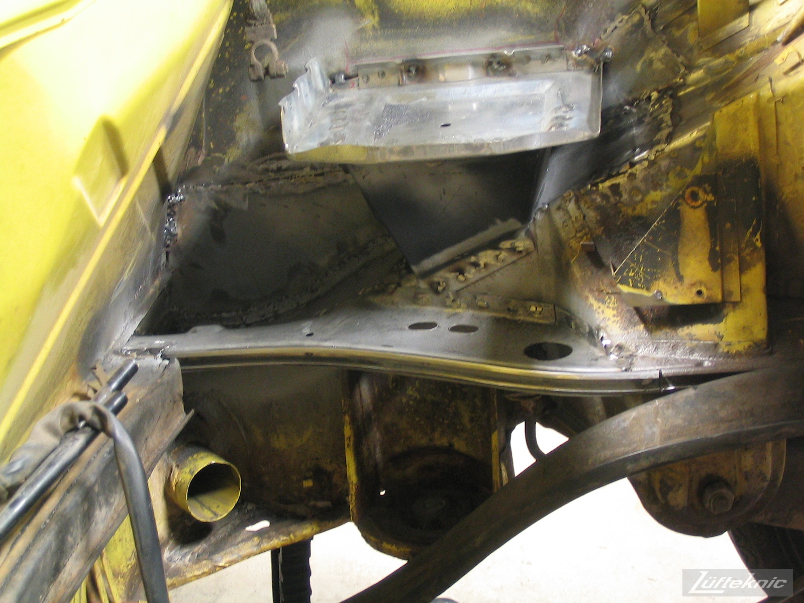 Repairing significant rust damage on the chassis of a yellow Porsche 914.