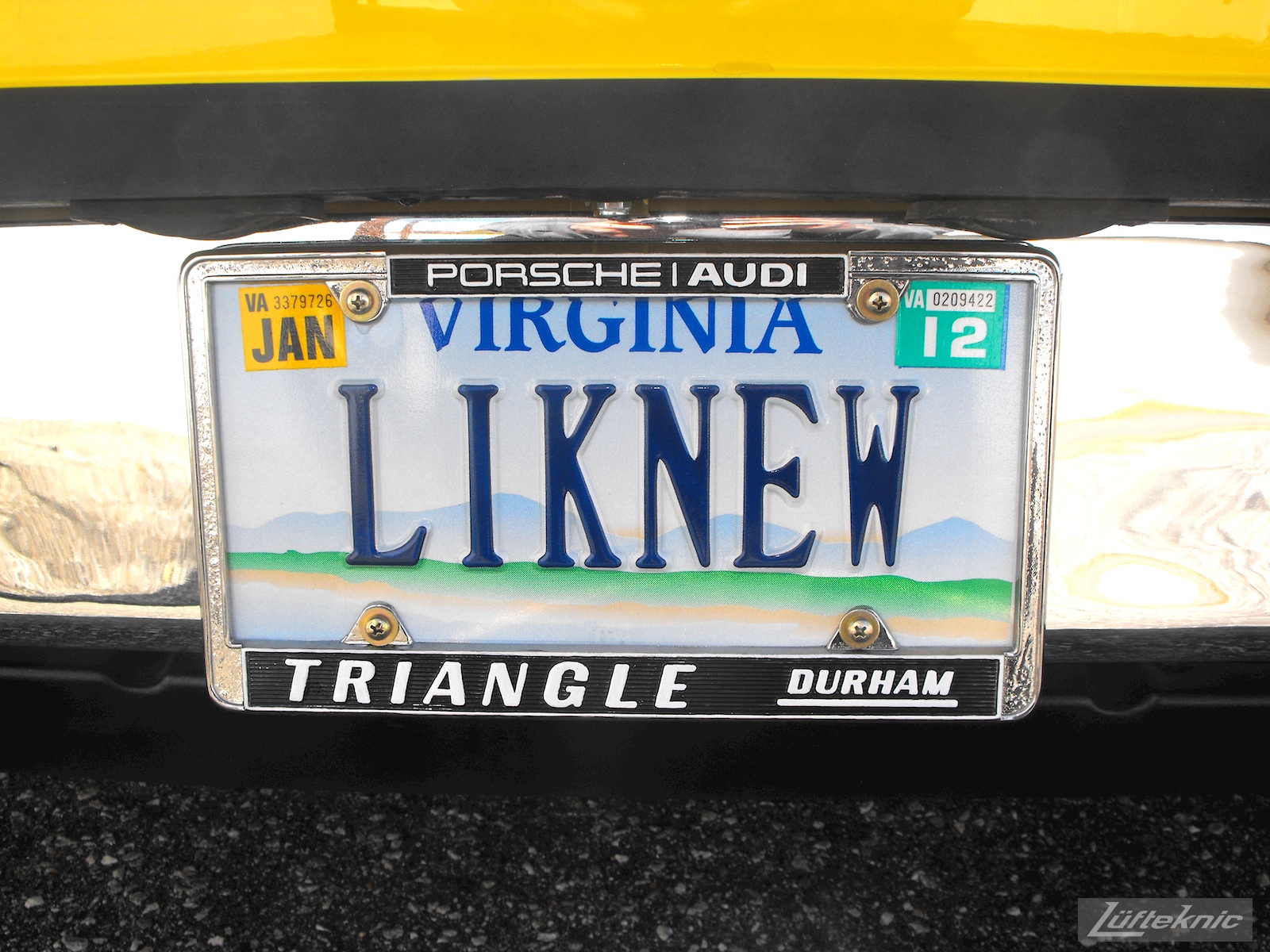 Restored original dealership license plate frame and "LIKENEW" vanity tag on a completely restored yellow Porsche 914 posing in the parking lot of Lufteknic.
