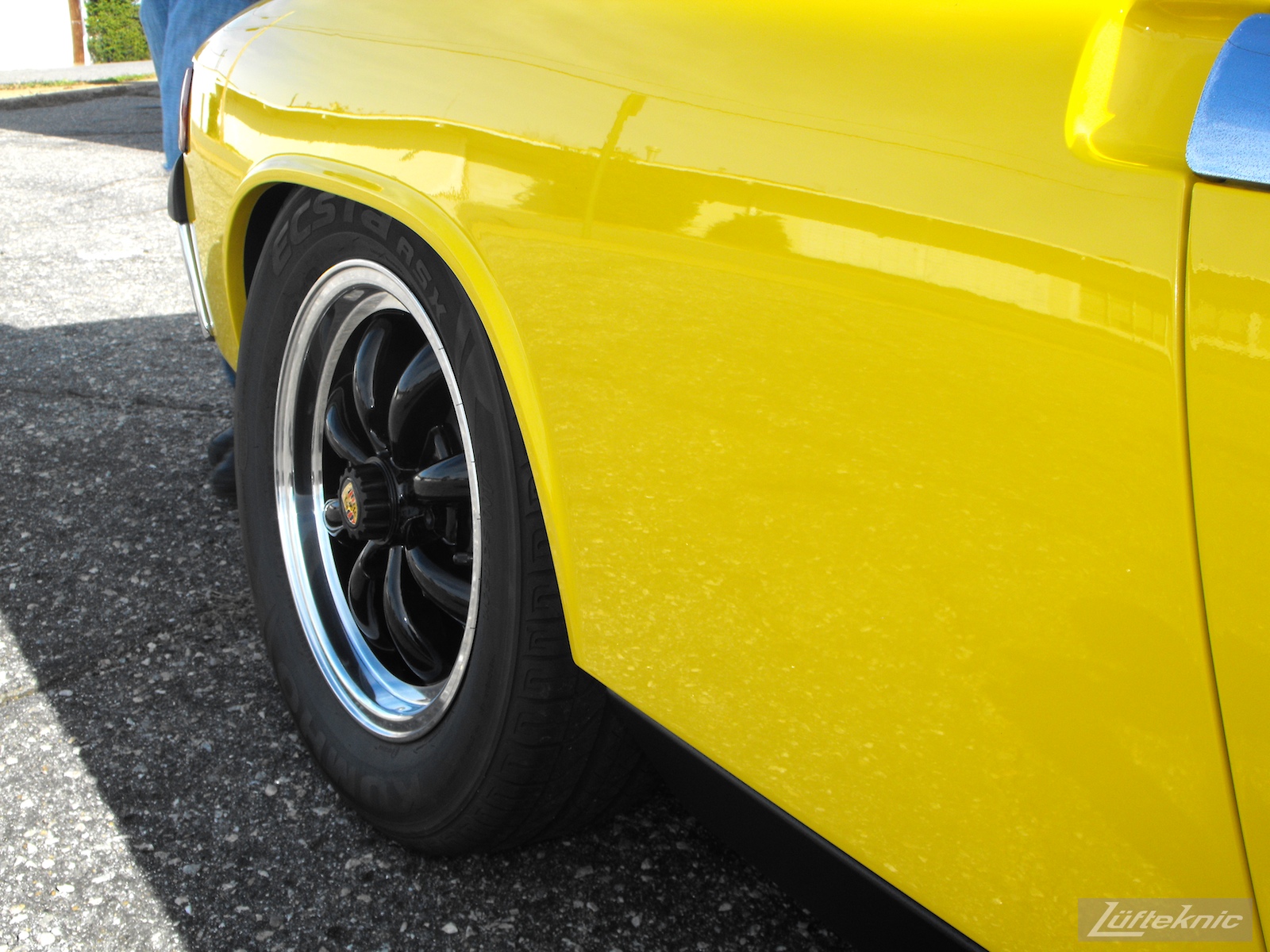 Rear quarter panel details of A completely restored yellow Porsche 914 posing in the parking lot of Lufteknic.