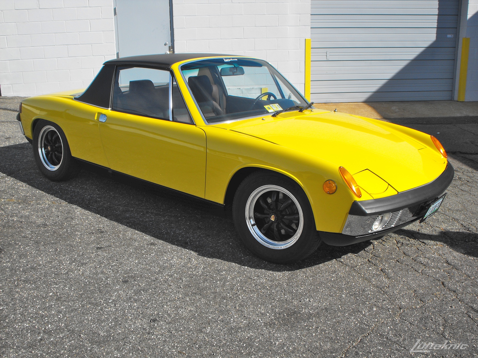 A completely restored yellow Porsche 914 posing in the parking lot of Lufteknic.