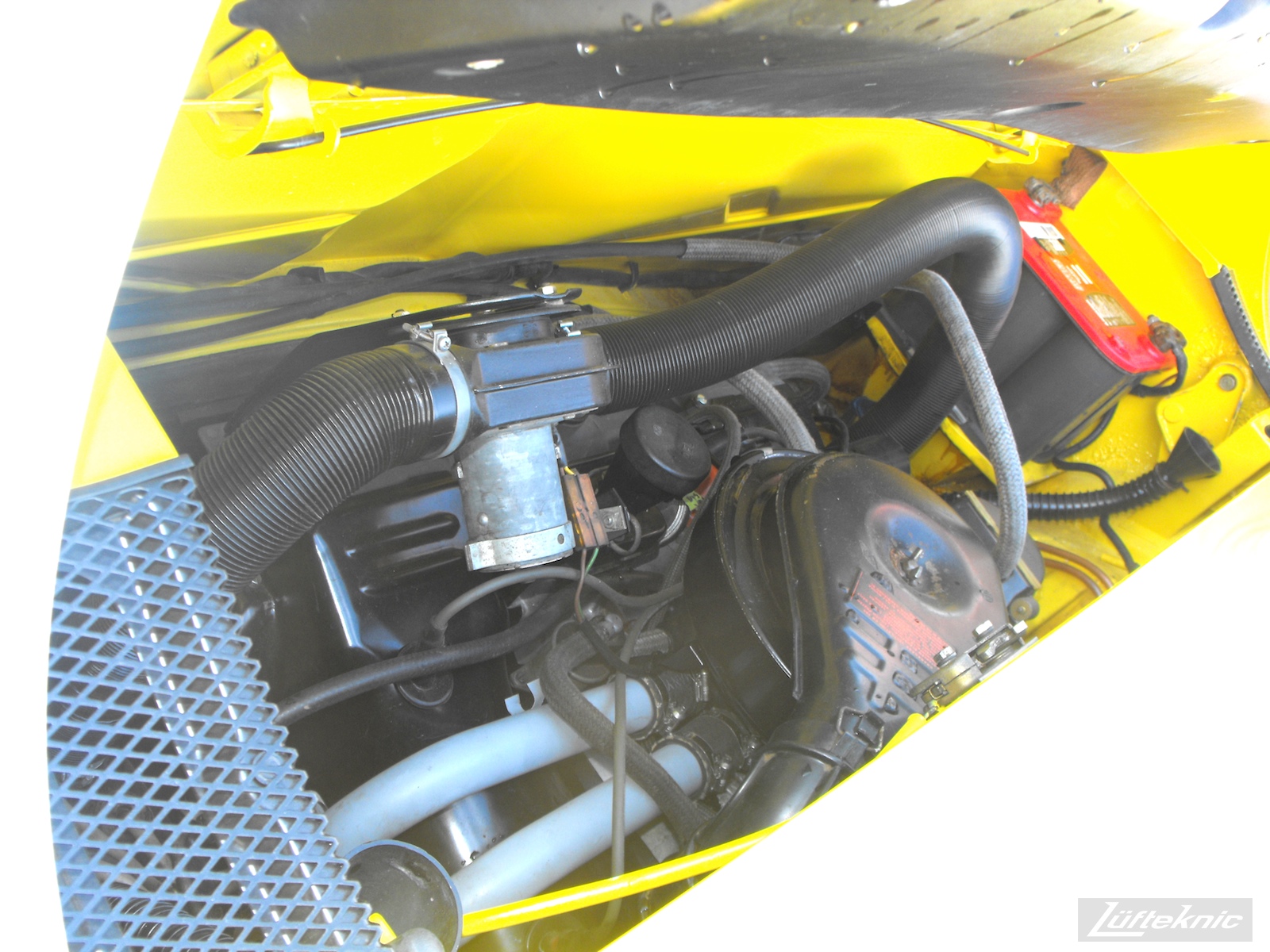 Engine detail photo of a completely restored yellow Porsche 914 posing in the parking lot of Lufteknic.