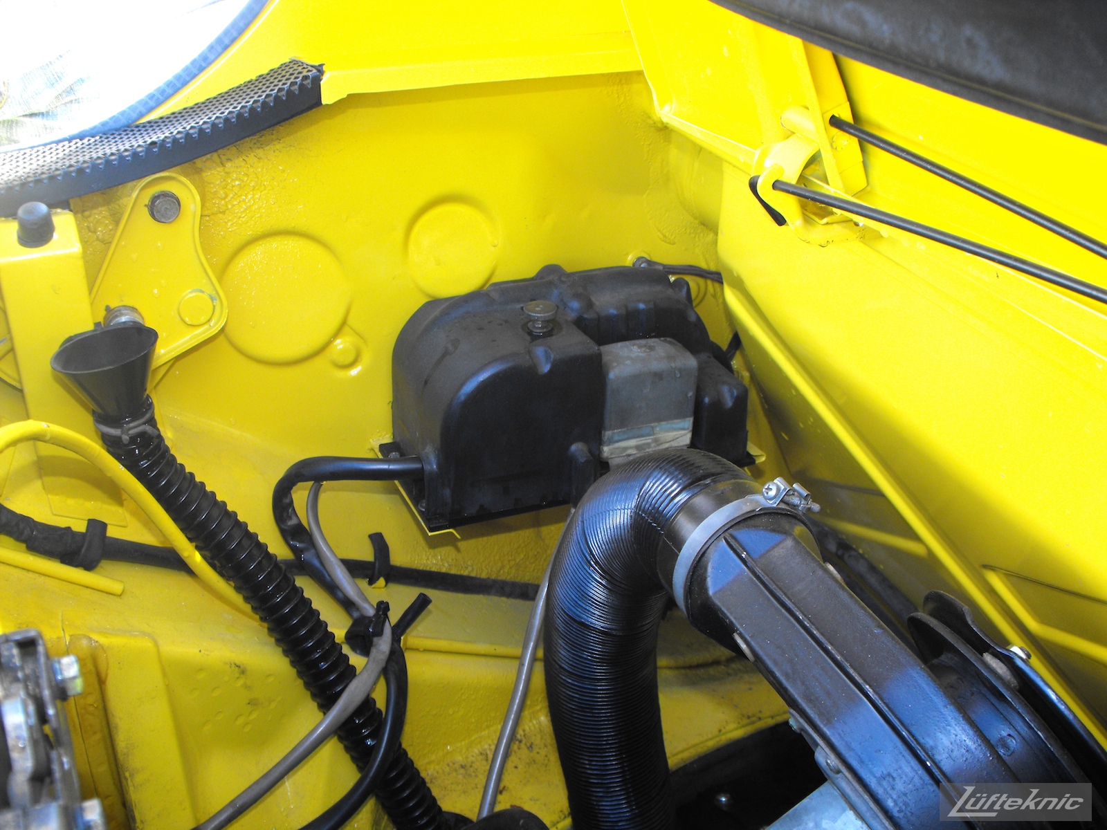 Engine details on a completely restored yellow Porsche 914 posing in the parking lot of Lufteknic.