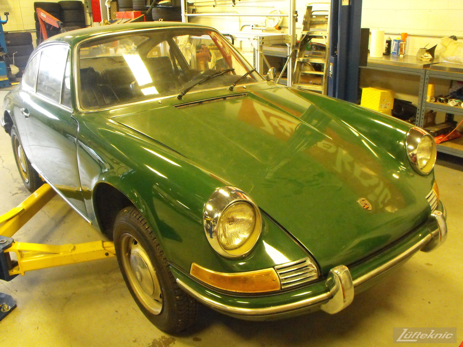 An Irish Green Porsche 912 undergoing restoration at Lufteknic with the car on a lift, showing original paint and trim.