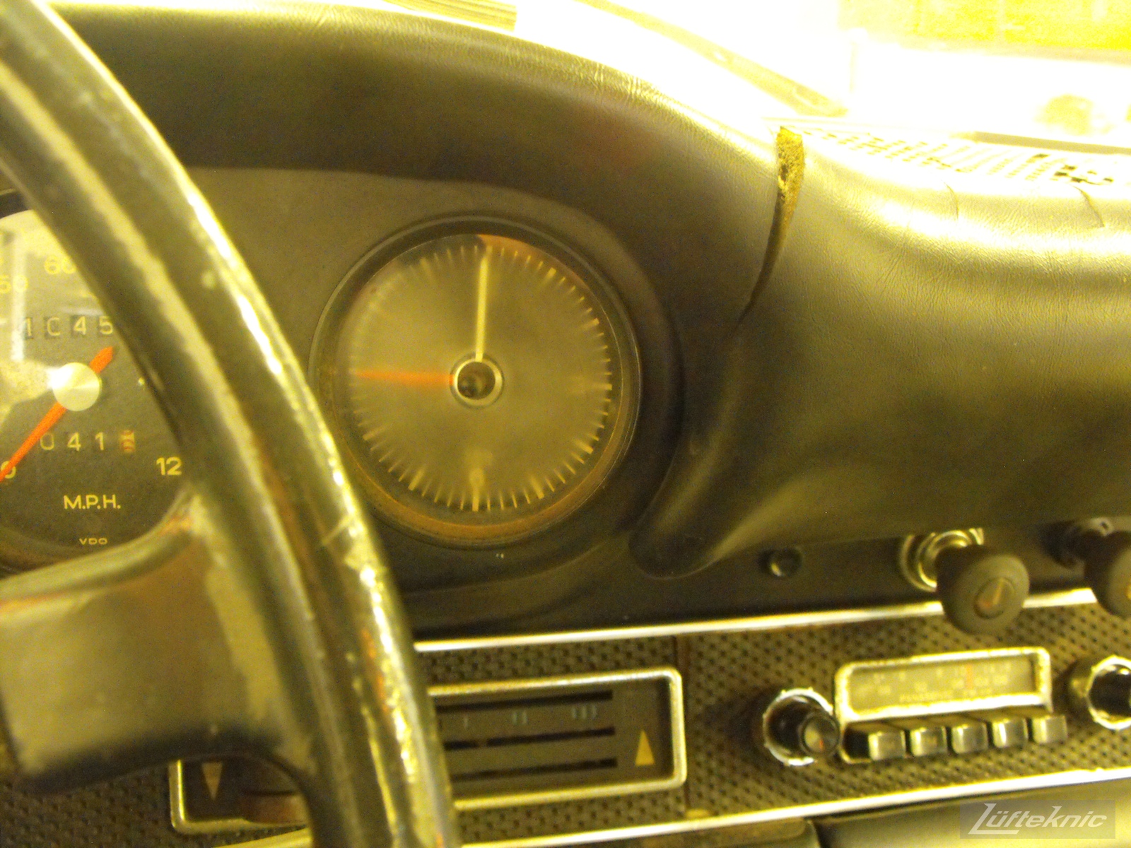 A close up of an aged clock and cracked dash of an Irish Green Porsche 912 undergoing restoration at Lufteknic.